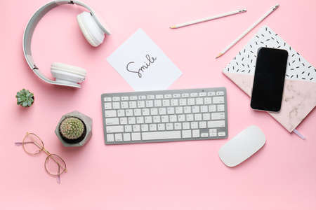 Computer keyboard with stationery, headphones and mobile phone on color backgroundの写真素材