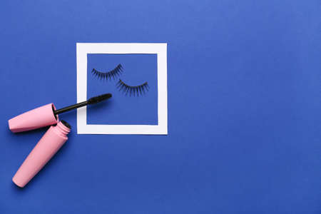 Mascara and fake eyelashes on color background