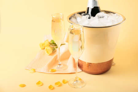 Bucket with ice, bottle of champagne and glasses on color backgroundの写真素材