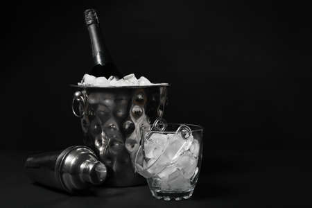 Bucket with ice, shaker and bottle of champagne on dark backgroundの写真素材