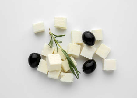 Tasty cut feta cheese with olives and herbs on white backgroundの写真素材