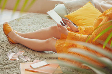 Makeup artist with modern tablet computer and decorative cosmetics sitting on floorの写真素材