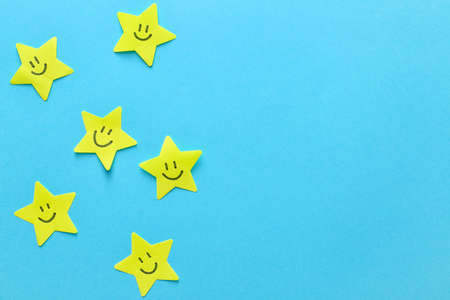 Paper stars with drawn happy faces on color backgroundの写真素材
