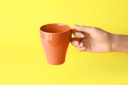 Female hand with Empty cup on color backgroundの写真素材