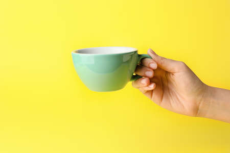 Female hand with Empty cup on color background