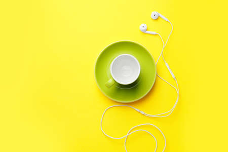 Empty cup and earphones on color backgroundの写真素材