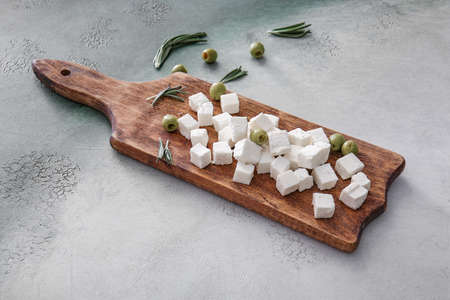 Board with tasty cut feta cheese and olives on tableの写真素材