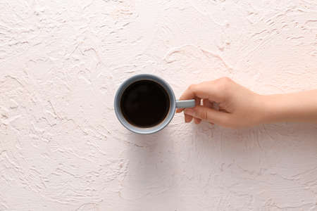 Female hand with cup of hot coffee on light background, top viewの写真素材