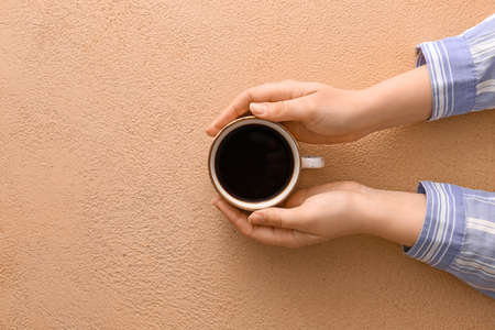 Female hands with cup of hot coffee on color background, top viewの写真素材