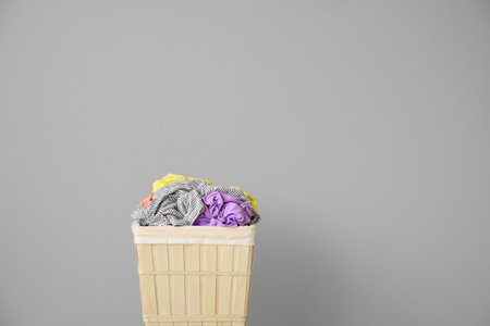 Wicker basket with laundry near light wallの写真素材