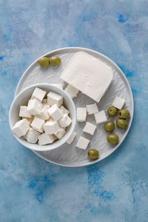 Plate with tasty cut feta cheese and olives on tableの写真素材