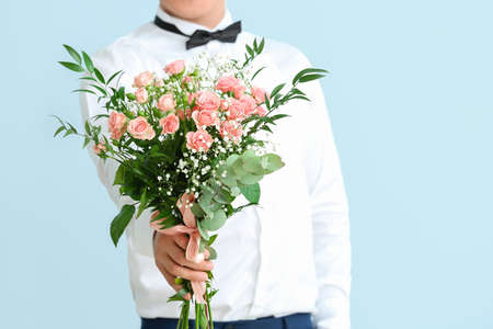 Handsome man with bouquet of flowers on color backgroundの写真素材