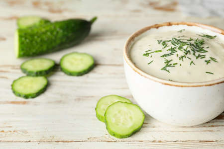 Delicious yogurt sauce with cucumber in bowl on white tableの写真素材