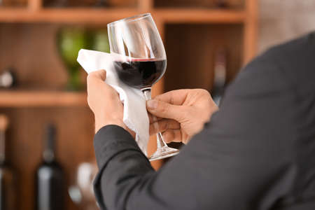 Man with glass of tasty wine and napkin in cellarの写真素材