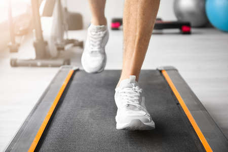 Young man training on treadmill in gym