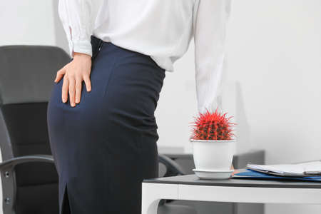 Young businesswoman with hemorrhoids in office