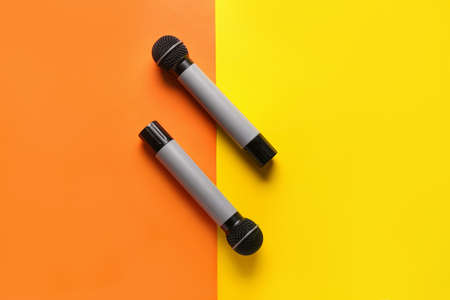 Modern microphones on color background