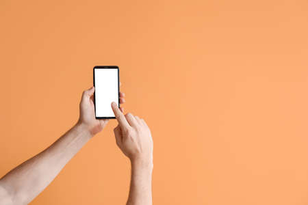 Male hands with mobile phone on color background