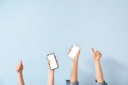 Female hands with mobile phones on light background