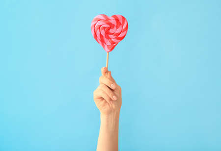 Hand with sweet lollipop on color backgroundの写真素材