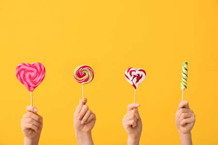 Hands with sweet lollipops on color backgroundの写真素材