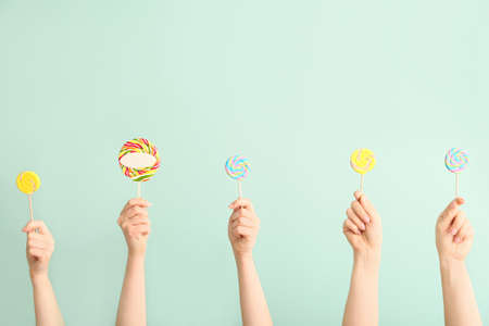 Hands with sweet lollipops on color backgroundの写真素材