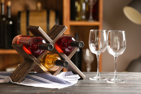 Stand with bottles of wine and glasses on table in cellarの写真素材