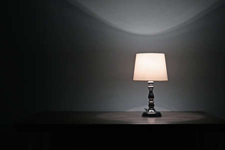 Glowing lamp on table in dark roomの写真素材