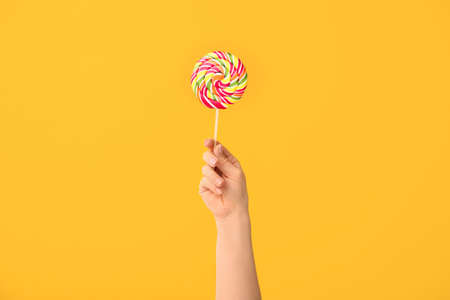Hand with sweet lollipop on color backgroundの写真素材