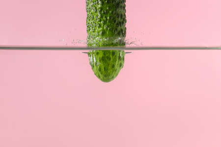 Falling of fresh cucumber into water against color backgroundの写真素材