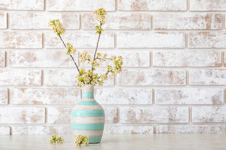 Vase with beautiful blooming branches on table in roomの写真素材