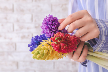 Woman with beautiful hyacinth flowers on brick background, closeupの写真素材