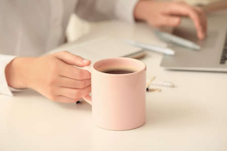 Woman with cup of tea working in office, closeupの写真素材