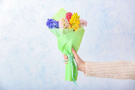 Female hand with beautiful hyacinth flowers on light backgroundの写真素材