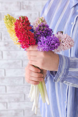 Woman with beautiful hyacinth flowers on brick background, closeupの写真素材