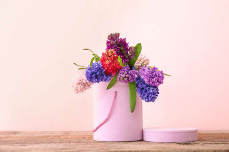 Box with beautiful hyacinth flowers on table against color backgroundの写真素材