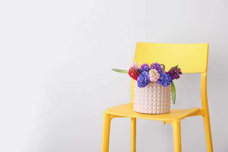 Vase with beautiful hyacinth flowers on chair against gray backgroundの写真素材