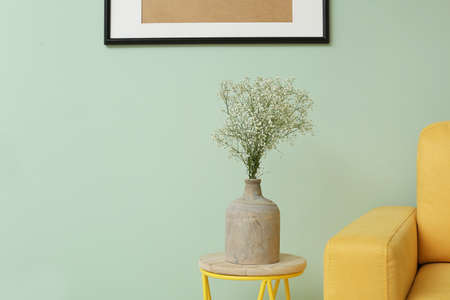 Stylish vase with beautiful bouquet on table near color wallの写真素材