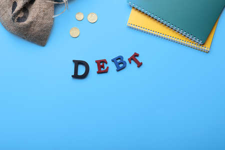 Bag with money, notebooks and word DEBT on color backgroundの写真素材
