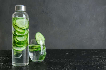 Glass and bottle of cucumber infused water on tableの写真素材