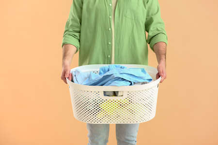 Young man with laundry on color backgroundの写真素材