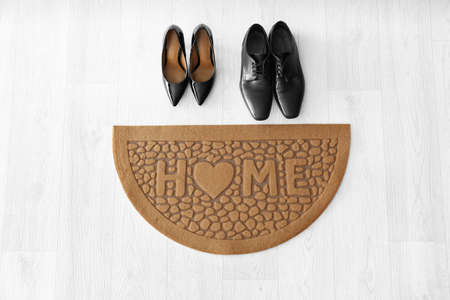 Door mat with shoes on wooden floorの写真素材
