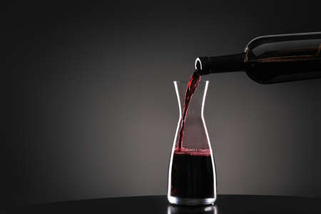 Pouring of tasty wine from bottle into glass on dark backgroundの写真素材