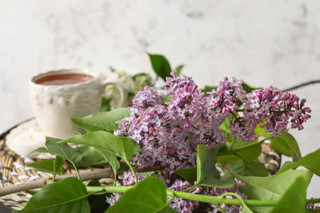 Beautiful lilac flowers with cup of tea on table, closeupの写真素材
