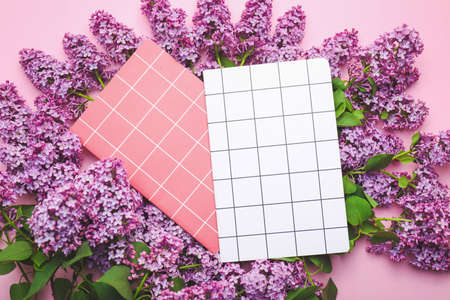 Beautiful lilac flowers and notebooks on color backgroundの写真素材