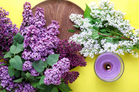Beautiful lilac flowers, plate and candle on color backgroundの写真素材