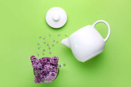 Composition with teapot and beautiful lilac flowers on color backgroundの写真素材