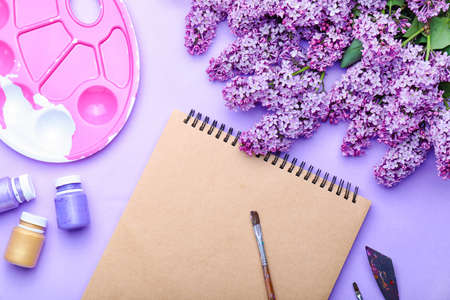 Beautiful lilac flowers and artist's supplies on color backgroundの写真素材