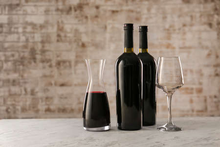 Decanter, bottles of wine and glass on tableの写真素材