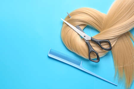 Long blonde hair, scissors and comb on color backgroundの写真素材